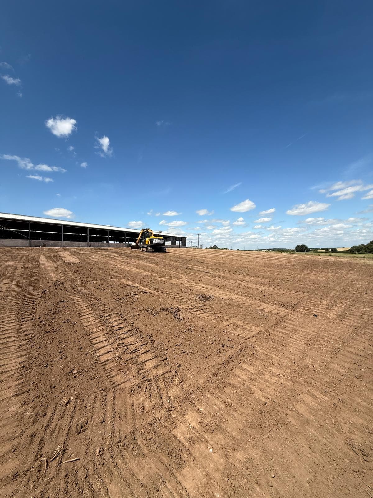 Excavator leveling a large field
